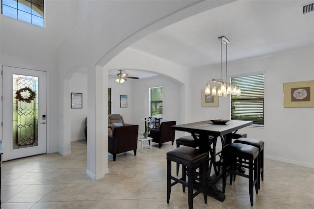 dining room with ceiling fan with notable chandelier, a wealth of natural light, light tile patterned floors, and ornamental molding