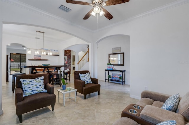 living room with ceiling fan with notable chandelier, crown molding, and light tile patterned floors