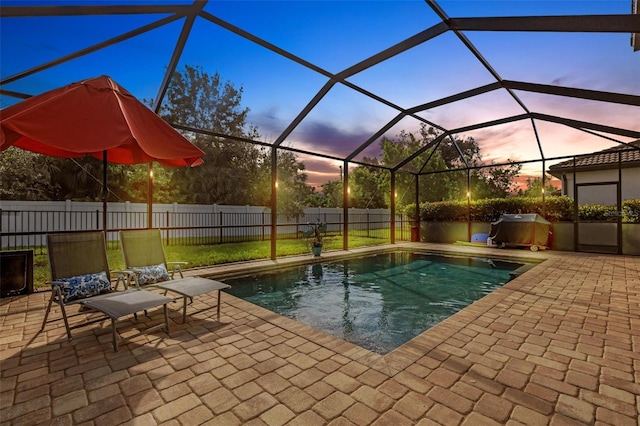 pool at dusk with glass enclosure, a lawn, and a patio