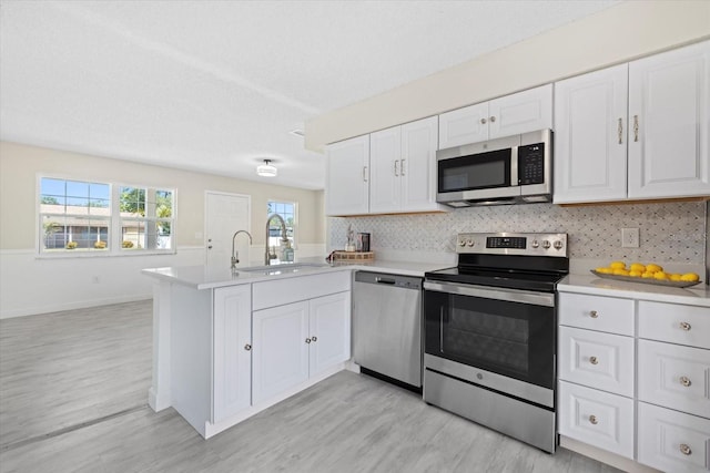 kitchen featuring white cabinetry, sink, stainless steel appliances, and kitchen peninsula