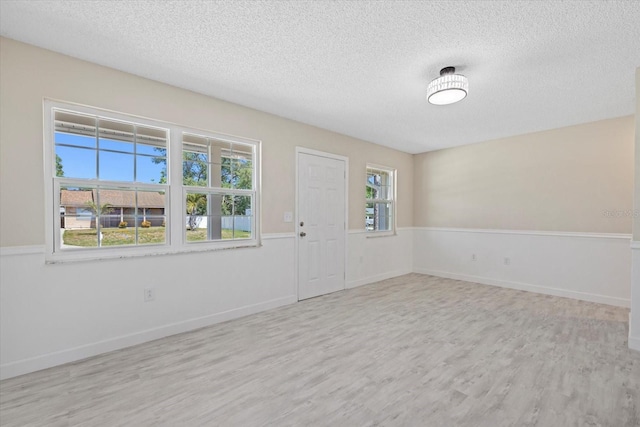 spare room with light hardwood / wood-style floors and a textured ceiling