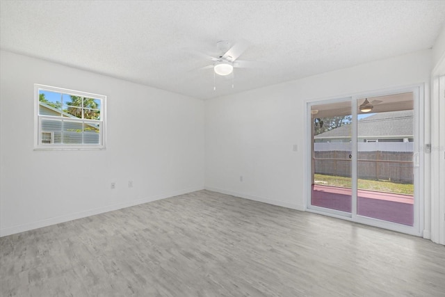 unfurnished room with ceiling fan, light wood-type flooring, and a textured ceiling