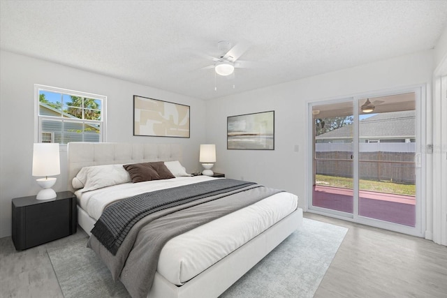 bedroom featuring ceiling fan, access to outside, a textured ceiling, and light hardwood / wood-style floors