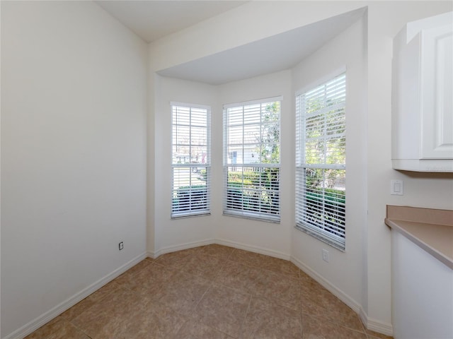 tiled spare room featuring a healthy amount of sunlight