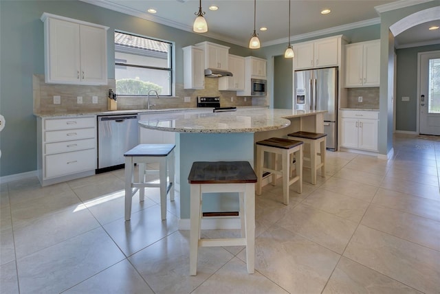 kitchen featuring white cabinetry, a center island, stainless steel appliances, and tasteful backsplash