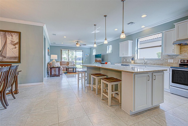 kitchen with stainless steel range with electric stovetop, white cabinetry, decorative backsplash, and a kitchen island