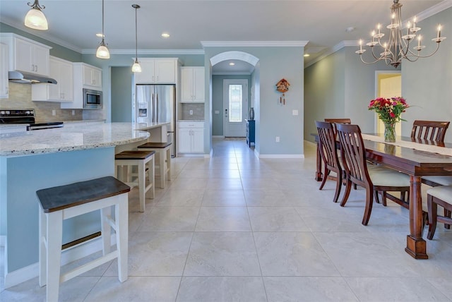 kitchen featuring appliances with stainless steel finishes, white cabinetry, a breakfast bar area, and tasteful backsplash