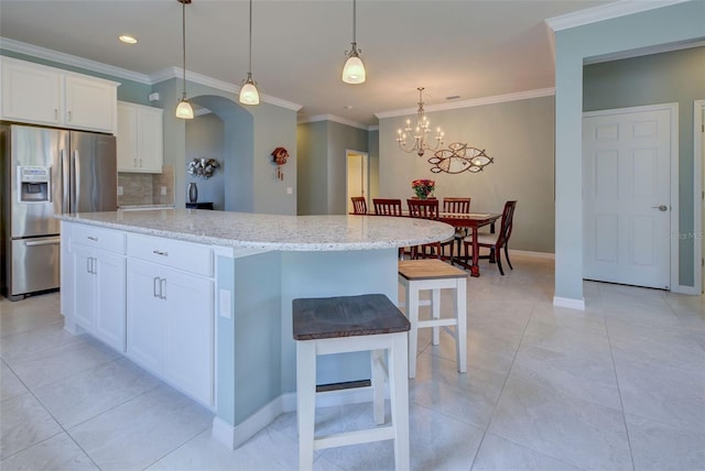 kitchen featuring a kitchen island, light stone countertops, stainless steel fridge with ice dispenser, and white cabinets