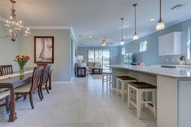 dining space with light tile patterned flooring, ceiling fan with notable chandelier, and crown molding