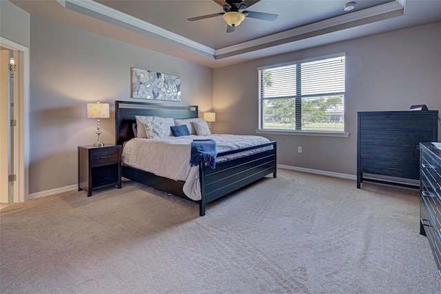 carpeted bedroom featuring ornamental molding, a tray ceiling, and ceiling fan