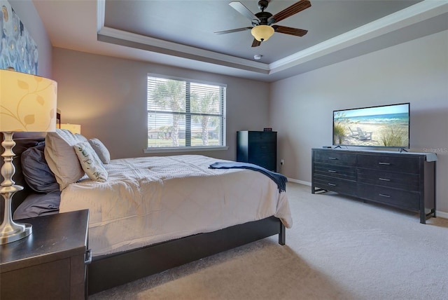 bedroom featuring ceiling fan, a raised ceiling, light carpet, and ornamental molding