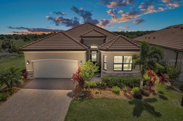 mediterranean / spanish-style house with a garage and a lawn