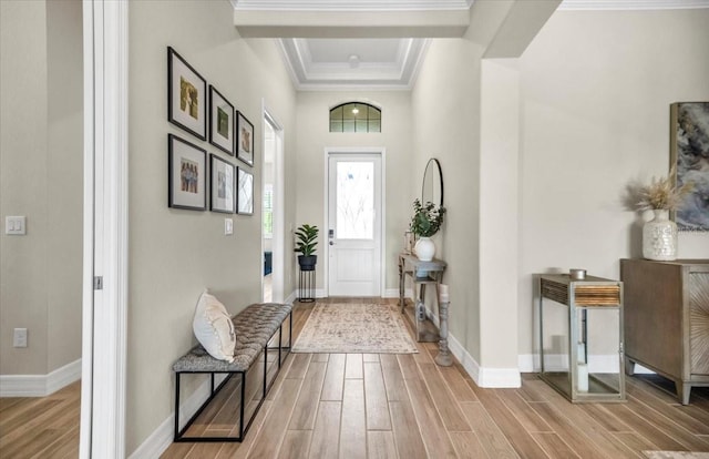 entrance foyer with ornamental molding, light hardwood / wood-style flooring, and a tray ceiling