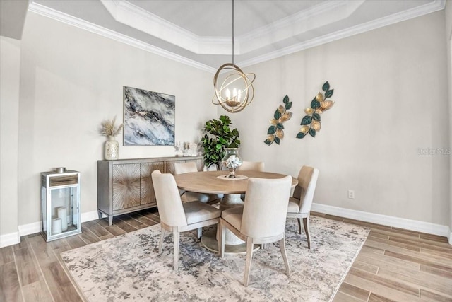 dining room with crown molding, hardwood / wood-style floors, and a raised ceiling