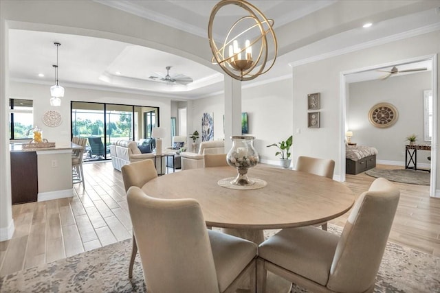 dining room featuring crown molding, ceiling fan with notable chandelier, light hardwood / wood-style floors, and a raised ceiling