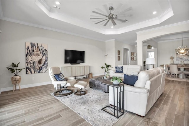 living room featuring crown molding, a tray ceiling, light wood-type flooring, and ceiling fan