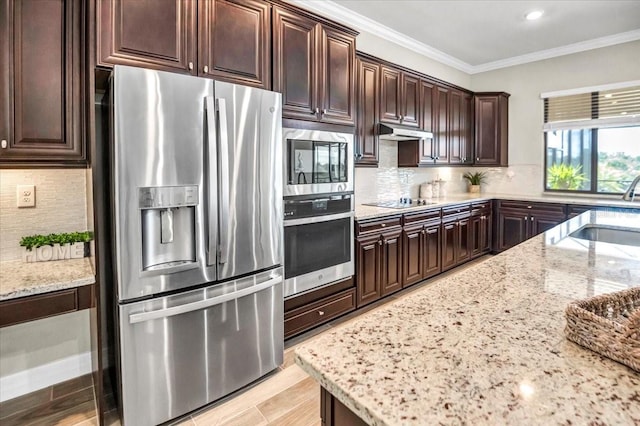 kitchen with light stone counters, appliances with stainless steel finishes, sink, and ornamental molding