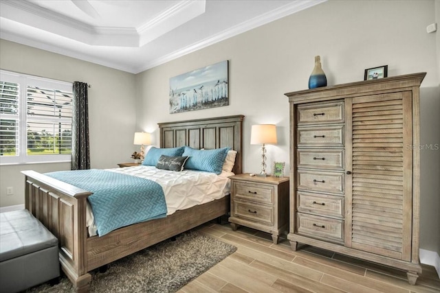 bedroom featuring light hardwood / wood-style floors, crown molding, a tray ceiling, and ceiling fan