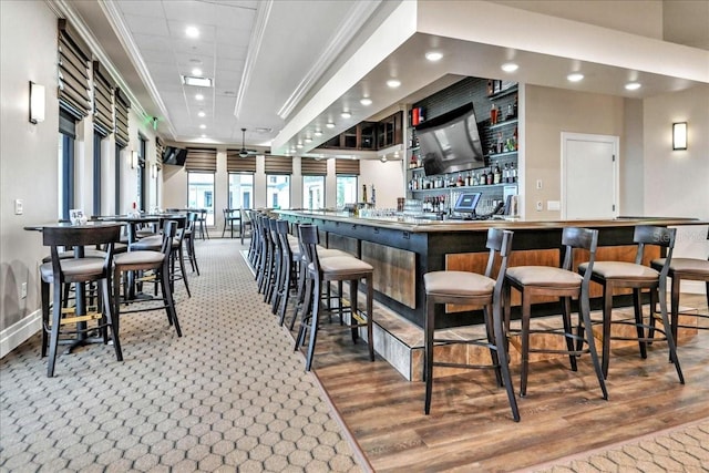 bar with ornamental molding and hardwood / wood-style floors