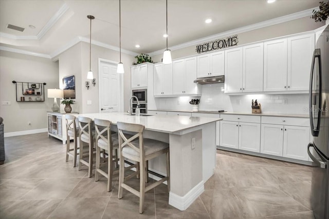 kitchen with white cabinetry, pendant lighting, crown molding, decorative backsplash, and a kitchen island with sink