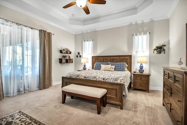 carpeted bedroom with crown molding, a tray ceiling, and ceiling fan