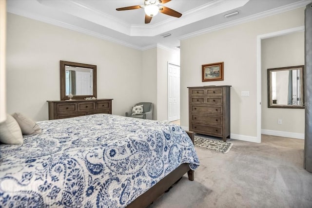 carpeted bedroom with a closet, ceiling fan, ornamental molding, and a tray ceiling