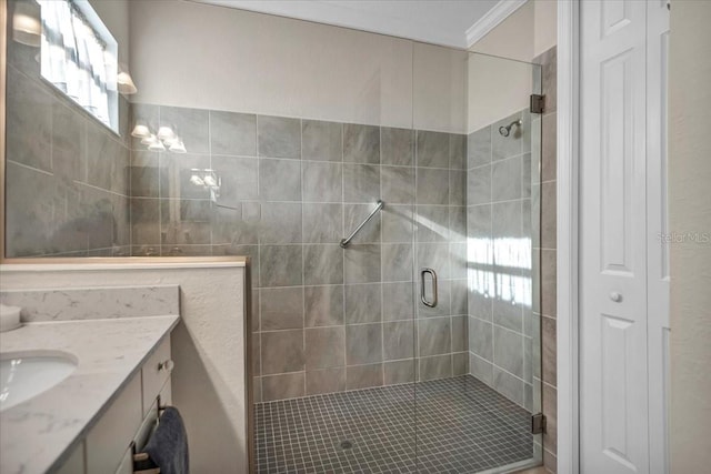 bathroom with a shower with door, vanity, and ornamental molding