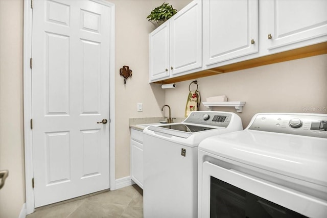 clothes washing area featuring sink, washer and dryer, cabinets, and light tile patterned floors