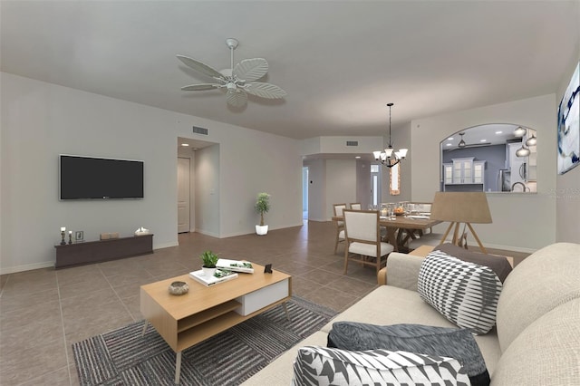 tiled living room with ceiling fan with notable chandelier