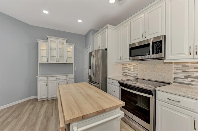 kitchen featuring stainless steel appliances, white cabinets, light wood-type flooring, and backsplash