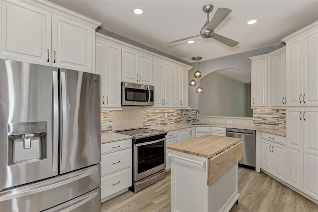 kitchen with appliances with stainless steel finishes, light hardwood / wood-style floors, white cabinetry, and light stone counters