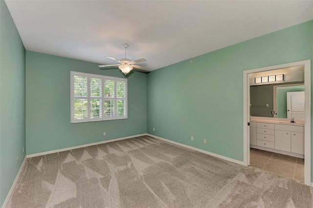 unfurnished bedroom with ceiling fan, light colored carpet, and ensuite bathroom