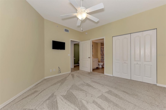 unfurnished bedroom with ensuite bath, ceiling fan, light colored carpet, and a closet