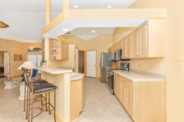 kitchen with appliances with stainless steel finishes, kitchen peninsula, a breakfast bar area, light brown cabinetry, and a chandelier