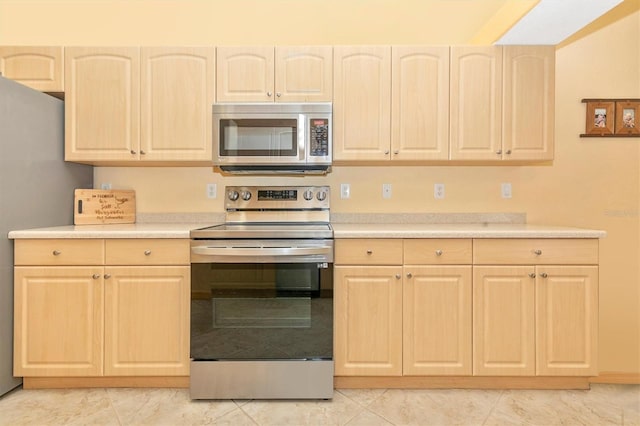 kitchen with light brown cabinetry, appliances with stainless steel finishes, and light tile patterned floors