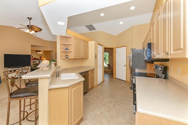 kitchen featuring appliances with stainless steel finishes, kitchen peninsula, light brown cabinetry, and a breakfast bar