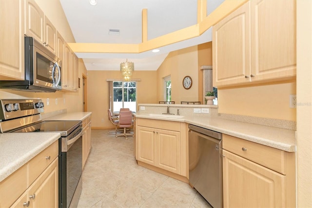 kitchen with vaulted ceiling, light brown cabinetry, pendant lighting, and stainless steel appliances