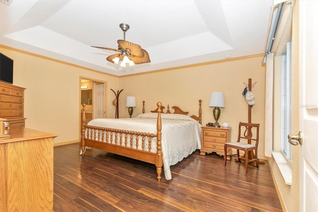 bedroom featuring ceiling fan, a raised ceiling, ensuite bathroom, and dark wood-type flooring