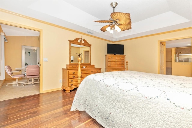 bedroom featuring ceiling fan, a raised ceiling, and wood-type flooring