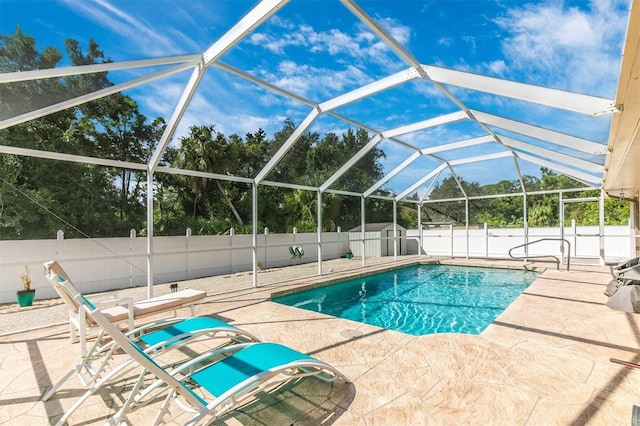 view of pool with glass enclosure and a patio area