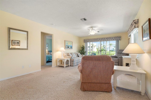 living room with ceiling fan, light colored carpet, and a textured ceiling