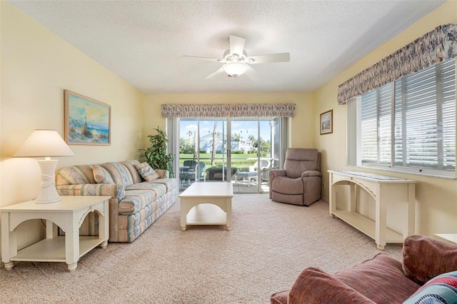 living room with light carpet, a textured ceiling, ceiling fan, and a healthy amount of sunlight