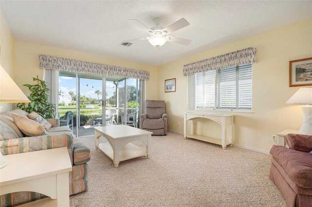 living room with ceiling fan, a textured ceiling, and light carpet