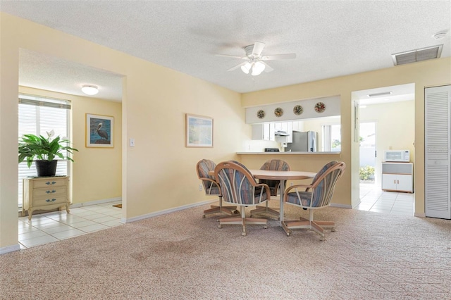 carpeted dining space with a textured ceiling and ceiling fan