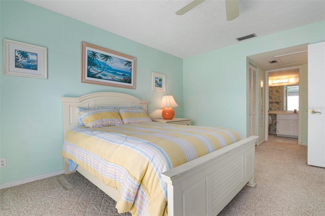 carpeted bedroom with ensuite bath, ceiling fan, and a textured ceiling