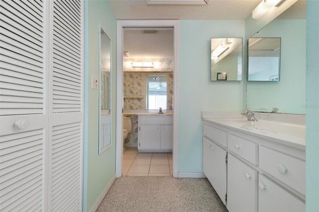 bathroom featuring tile patterned flooring, a textured ceiling, vanity, and toilet