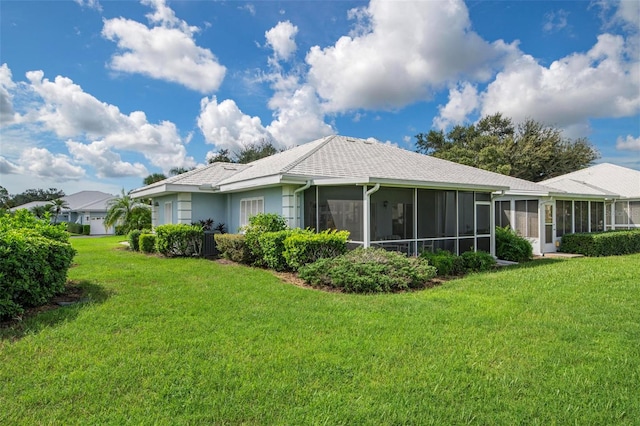 back of property with a sunroom and a lawn