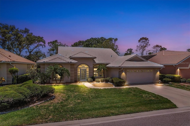 mediterranean / spanish house with a garage and a lawn