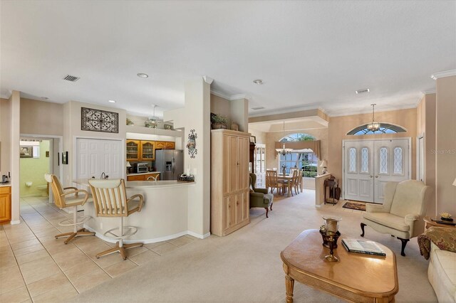 living room featuring an inviting chandelier, light tile patterned flooring, and ornamental molding