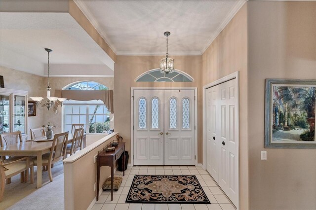 tiled entrance foyer featuring crown molding and a chandelier